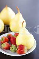 strawberry  in plate and pear on a wooden table