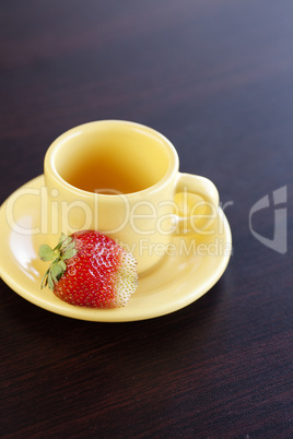 strawberries and a cup with saucer on a wooden table