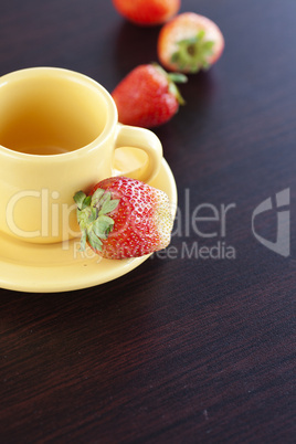 strawberries and a cup with saucer on a wooden table