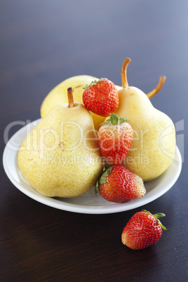 strawberries and  pears on a plate on a wooden table