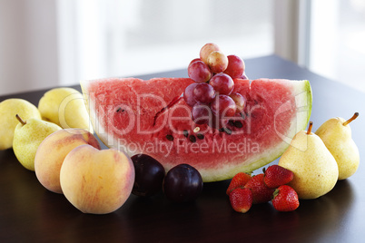 watermelon, strawberry, grape, plum and pear lying on a wooden t