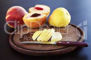 peach, pear and a knife on a cutting board