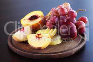 peach, pear and grapes on a cutting board