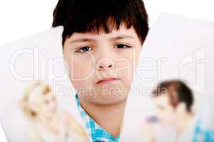 Upset boy standing in front pcture of parents with problems agai