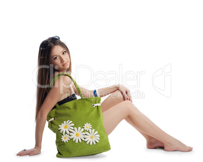 Girl sit with green beach bag isolated on white