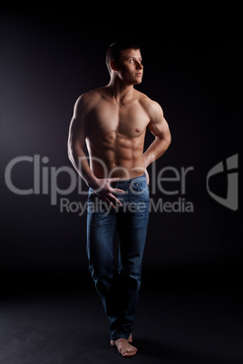 man with naked torso in jeans posing from dark