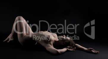 Nude young woman lay in dark