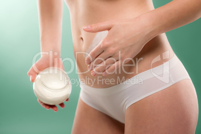 Woman apply body cream on belly