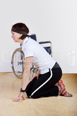 Frau kniet vor dem Rollstuhl