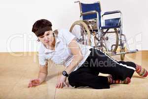 Frau liegt vor dem Rollstuhl auf dem Boden