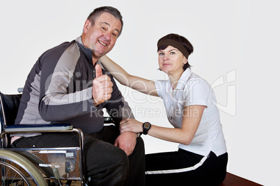 Frau sitzt neben Mann im  Rollstuhl der zuversichtlich ist