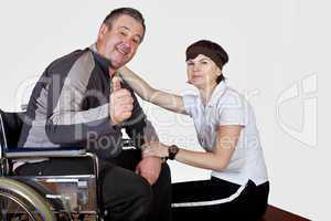 Frau sitzt neben Mann im  Rollstuhl der zuversichtlich ist