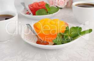 A cup of coffee and orange jelly with slices of fresh orange
