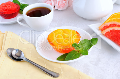 A cup of coffee and orange jelly with slices of fresh orange