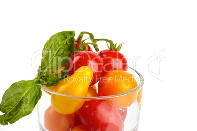 Ein Glas gefüllt mit bunten frischen kleinen Bio Tomaten vor weißem Hintergrund