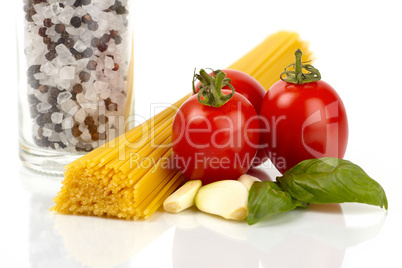 Spaghetti Nudeln mit Tomaten, Basilikum und Knoblauchzehen vor weißem Hintergrund