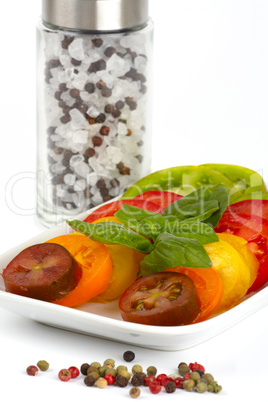 Tomatenscheiben verschiedener Biosorten auf einem Teller vor weißem Hintergrund