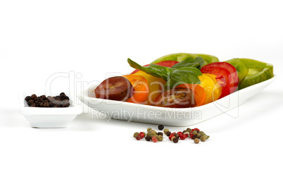 Tomatenscheiben verschiedener Biosorten auf einem Teller vor weißem Hintergrund