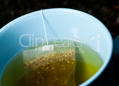 Green tea brewing in hot water in blue cup