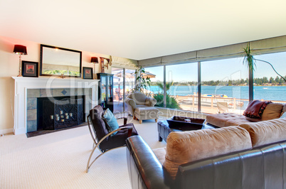Living room with fireplace and water view with large windows.