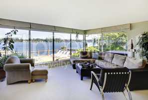 Living room with fireplace and water view with large windows.