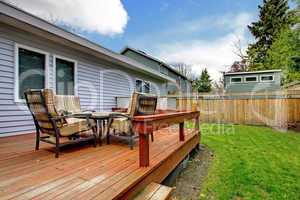 Grey small house with simple deck and outdoor chairs.