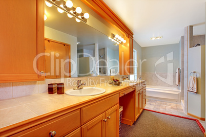 Large bathroom with double sinks and tub with grey rug.