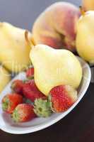 strawberry  in plate, pear and peach on a wooden table