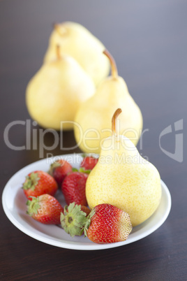 strawberry  in plate, pear and peach on a wooden table