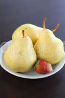 strawberry in plate and pear on a wooden table