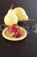 strawberry in plate and pear on a wooden table