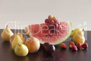watermelon, strawberry, grape, plum and pear lying on a wooden t