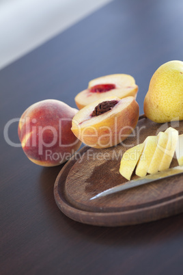 peach, pear and a knife on a cutting board