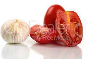 Frische Tomaten mit Knoblauchzwiebel vor weißem Hintergrund