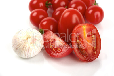 Frische Tomaten mit Knoblauchzwiebel vor weißem Hintergrund