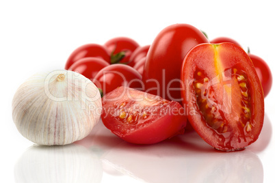 Frische Tomaten mit Knoblauchzwiebel vor weißem Hintergrund