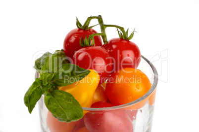 Ein Glas gefüllt mit bunten frischen kleinen Bio Tomaten vor weißem Hintergrund