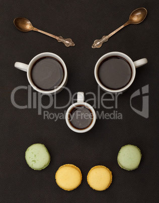 Tree cups coffee and macaroon arranged in happy face