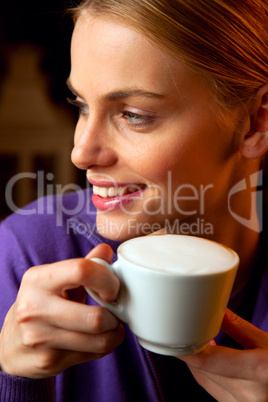 young woman drinking cappuccino smiling portrait close-up