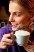 young woman drinking cappuccino smiling portrait close-up