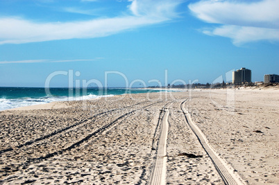 Car track on white sand beach