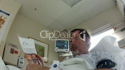 Patient man reading surgery results in bed P HD 0012
