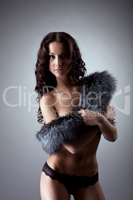 Young naked woman stand and close breast by fur