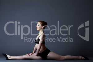 Beauty girl in black gymnast costume sit on split