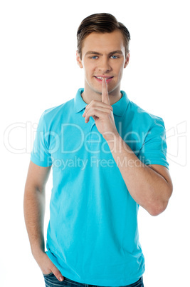 Silence gesture by a young guy wearing blue t-shirt