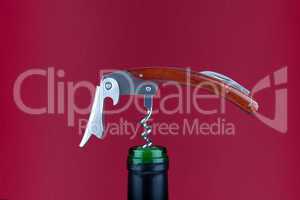 Korkenzieher in Weinflasche vor rotem Hintergrund