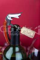 Korkenzieher mit Korken liegt auf Flaschenhals einer Weinflasche