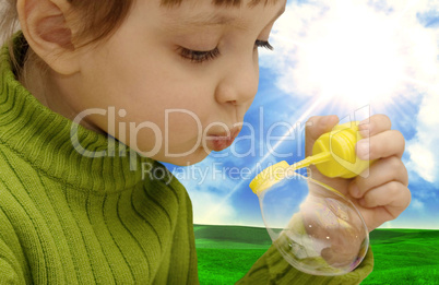 The girl inflating soap bubbles on a meadow
