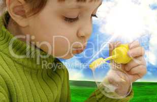 The girl inflating soap bubbles on a meadow