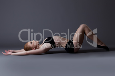 young gymnast girl in black top lay on background